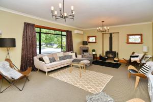 uma sala de estar com um sofá e cadeiras e uma lareira em Racecourse Villa - Christchurch Holiday Home em Christchurch