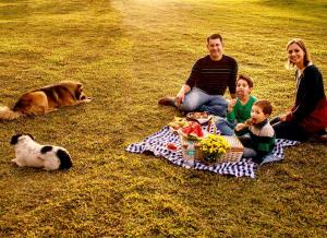 a family sitting on a picnic blanket with a dog at Tedesco Eco Park in São Francisco de Paula