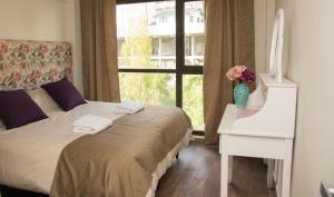 1 dormitorio con cama, escritorio y ventana en La Bonita Apartment en San Carlos de Bariloche