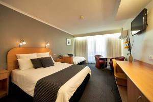 a hotel room with a bed and a desk at Beachfront Voyager Motor Inn in Burnie