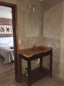 Un baño con lavabo de madera y espejo. en La Posada, en Villa Ventana