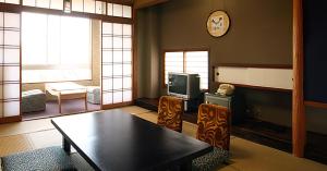 een woonkamer met een tafel en een televisie bij Hotel Ikaho Ginsui in Shibukawa