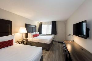 a hotel room with two beds and a flat screen tv at SureStay Hotel by Best Western Castlegar in Castlegar
