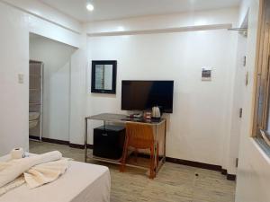 ボラカイにあるMagarbo Hotelのデスク、テレビ、ベッドが備わる客室です。