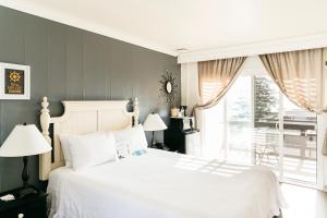 Un dormitorio con una gran cama blanca y una ventana en Seaside Laguna Inn & Suites, en Laguna Beach