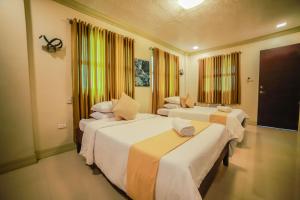 a hotel room with three beds in it at Villa Esmeralda Bryan's Resort Hotel and Restaurant in Palayan City