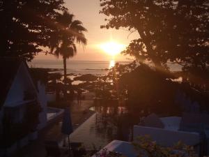 a sunset over the ocean and a beach with trees at Ocean Breeze Resort Khaolak in Khao Lak