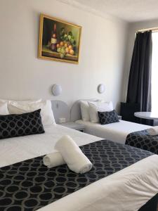 um quarto de hotel com duas camas e um quadro na parede em Queanbeyan Motel em Queanbeyan