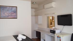 Habitación con escritorio y TV en la pared. en Queanbeyan Motel, en Queanbeyan