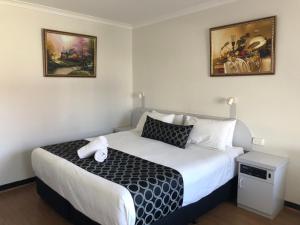Schlafzimmer mit einem Bett mit einer schwarzen und weißen Bettdecke in der Unterkunft Queanbeyan Motel in Queanbeyan