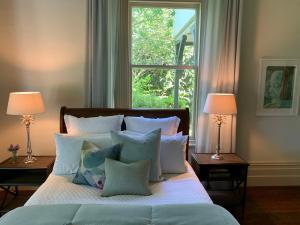 ein Schlafzimmer mit einem Bett mit Kissen und einem Fenster in der Unterkunft The Vicarage Boutique Bed and Breakfast Oamaru in Oamaru