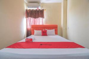 a bedroom with a bed with red and white pillows at RedDoorz Syariah At Jalan cilik Riwut Kapuas in Kualakapuas
