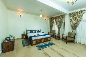 a bedroom with a king sized bed and a chair at StayVista at Garbyang Homestay in Nainital