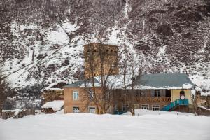 un bâtiment dans la neige devant une montagne dans l'établissement Guesthouse Tanano/Dodo, à Zhabeshi