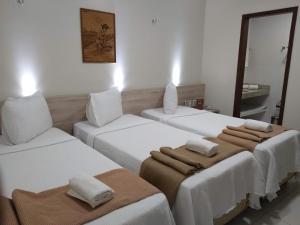 a room with three beds with towels on them at Hotel Padre Cícero in Juazeiro do Norte