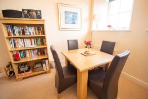 a dining room table with chairs and a book shelf at Kilchoman in Port Charlotte