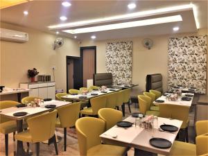 a dining room with tables and yellow chairs at Hotel Bharat in Kota