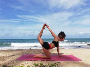 a woman doing a yoga pose on the beach at Non La Mer Hostel - Bed & Yoga in Ko Lanta