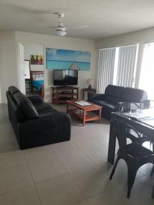 a living room with two black couches and a tv at Bayview Harbourview Apartments in Mooloolaba