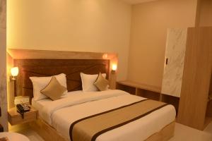 コーターにあるHotel Bharatのベッドルーム1室(大型ベッド1台、白いシーツ、枕付)