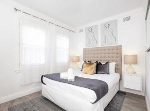a white bedroom with a large bed and two windows at The Great Escape Bellevue Hill in Sydney