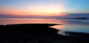 an island in the water with a sunset in the background at Pano Resort in Ko Mak