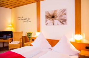 a bedroom with a bed with white sheets and a flower on the wall at Pension Zum Schmidbäcker in Freyung
