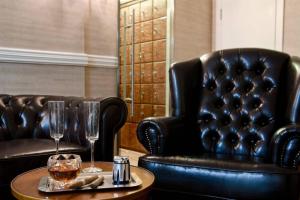 two black leather chairs and a table with two glasses at 107 - King David Residence - Jerusalem-Rent in Jerusalem
