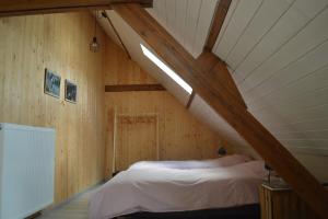 a bedroom with a bed in a wooden attic at De Bossenaarshoeve in Maarkedal