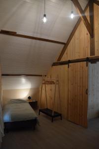 een slaapkamer met een bed en een houten muur bij De Bossenaarshoeve in Maarkedal