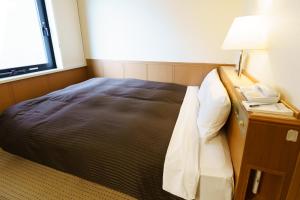 a hotel room with a bed and a phone and a window at Kyoto Horikawa Inn in Kyoto