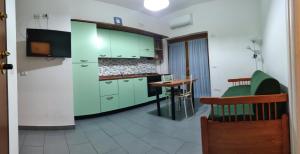 a kitchen with green cabinets and a table in it at Flat House in Fiumicino