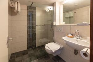 La salle de bains est pourvue de toilettes, d'un lavabo et d'une douche. dans l'établissement Amsterdam Wiechmann Hotel, à Amsterdam