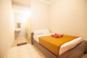 a bedroom with a bed with a red flower on it at Putra Dadi Guest House in Canggu