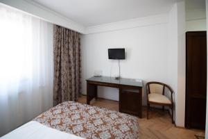 1 dormitorio con 1 cama y escritorio con TV en Pension Arena, en Cluj-Napoca