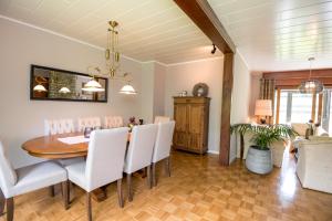 jadalnia ze stołem i białymi krzesłami w obiekcie Ferienhaus Maison Idylle im Hohen Venn - Monschau w mieście Bütgenbach