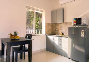 a kitchen with a table and a refrigerator at Passions de Goa in Anjuna