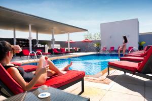 a group of people sitting on chairs next to a pool at Centro Barsha - by Rotana in Dubai