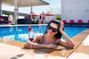 una mujer en una piscina con una copa de vino en Centro Barsha - by Rotana, en Dubái