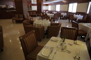 a dining room with white tables and chairs and tablesearcher at Rain Drops Hotel in Chennai