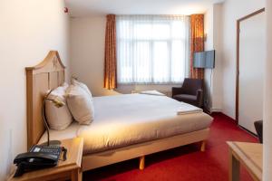 ein Hotelzimmer mit einem Bett und einem Telefon in der Unterkunft Amsterdam Wiechmann Hotel in Amsterdam