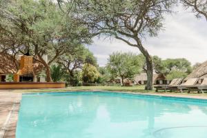 einen Pool in einem Garten mit Bäumen in der Unterkunft Okahandja Country Hotel in Okahandja