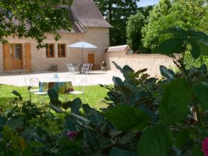 einen Garten mit einem Tisch und einem Sonnenschirm vor einem Haus in der Unterkunft Maison Périgord Noir près de Lascaux, Montignac, Sarlat, Périgueux in Fleurac