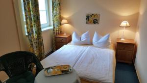 ein Hotelzimmer mit einem Bett mit weißer Bettwäsche und Kissen in der Unterkunft Pension Am Holzgraben in Lübbenau