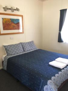 a bedroom with a blue bed with two pillows on it at Scenic Rim Motel in Aratula