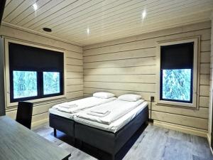 a bedroom with a bed in a room with two windows at Levillas Kuppimaantie Villas in Levi +35 photos