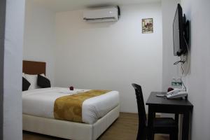 a bedroom with a bed and a table with a telephone at Big Apple Hotel in Kulim