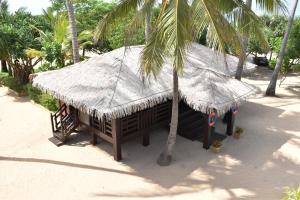a hut with a straw roof and a palm tree at Nilaveli Beach Resort - Level 1 Certified in Nilaveli