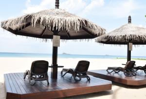 a group of chairs under an umbrella on the beach at Nilaveli Beach Resort - Level 1 Certified in Nilaveli