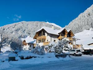una casa cubierta de nieve con una montaña en el fondo en Apartments Grossgasteiger, en Rio Bianco